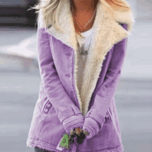 a woman is wearing a purple coat with a fur collar