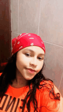 a girl wearing a red bandana and an orange shirt that says ' oiie ' on it