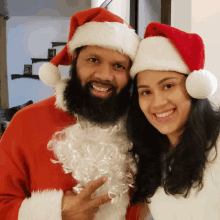 a man with a beard and a woman wearing santa hats pose for a photo