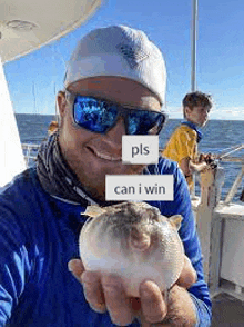 a man wearing sunglasses is holding a puffer fish in his hands on a boat .