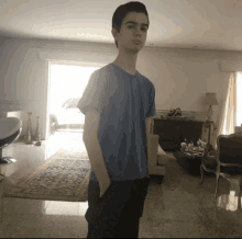 a boy in a blue shirt is standing in a living room