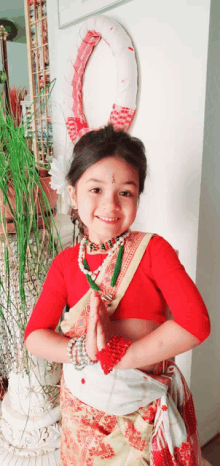 a little girl wearing a red top and white skirt is smiling