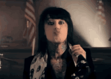 a woman with tattoos on her face is blowing a kiss in front of an american flag