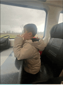 a young boy is sitting in a car looking out the window