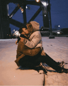 a man and a woman kissing in the snow while holding sparklers