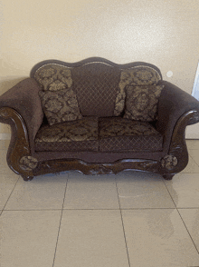 a brown couch with gold pillows sits on a tile floor