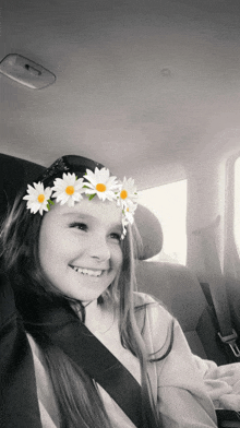 a little girl wearing a flower crown smiles in a car