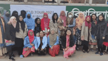 a group of women are posing for a photo in front of a sign that says ' eid tour 2021 '