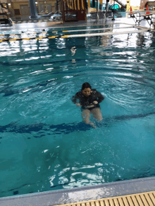 a woman is swimming in a pool with a slide in the background