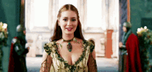 a woman in a green and gold dress is smiling in a room