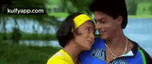 a man and a woman are kissing in a park . the woman is wearing a yellow headband .