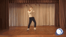 a man is dancing on a stage in front of a curtain with a globe in the corner