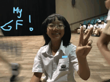 a girl giving a peace sign in front of a sign that says my gf on it