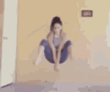 a woman is jumping in the air while doing a handstand in a room .