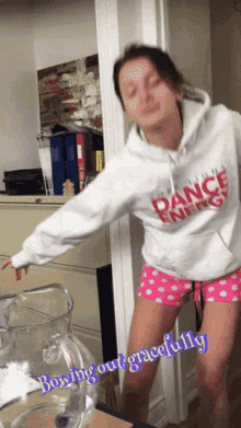 a woman wearing a dance energy hoodie stands in a doorway