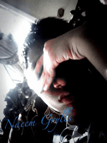 a person covering their face with their hand with the name naeem graytts written in blue