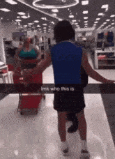 a man in a blue shirt is standing next to a woman pushing a shopping cart in a target store .