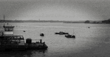 a black and white photo of a body of water with boats in it and a boat that says ' sydney ' on it