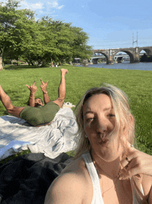 a man laying on a blanket with his legs up and a woman blowing a kiss