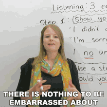 a woman stands in front of a white board with the words " there is nothing to be embarrassed about "