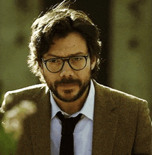 a man with a beard is wearing glasses and a suit and tie .