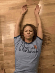 a woman wearing a virginia is for lovers shirt is laying on the floor