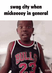 a young boy wearing a bulls jersey is making a funny face while standing in front of a white wall .