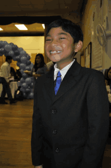 a young boy in a suit and tie is smiling