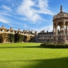 a large lawn with a building in the background and a gazebo in the foreground