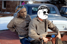 two men are riding a motorcycle with one wearing sunglasses and a helmet