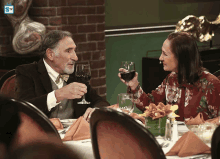 a man and woman are toasting with wine glasses in a restaurant