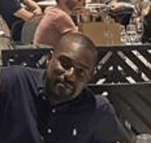 a man in a blue shirt is sitting at a table in a restaurant .