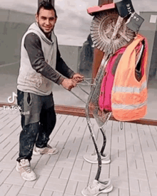 a man is standing next to a statue of a person with a wheel on their back .