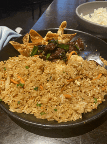 a plate of fried rice with meat and wonton sticks