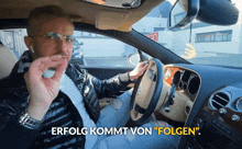 a man smoking a cigarette in a car with the words " erfolg kommt von folgen "