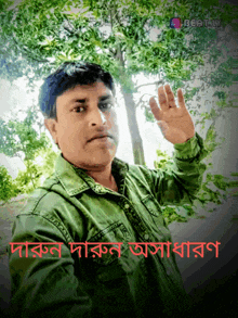 a man in a green shirt waves his hand in front of trees