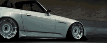 a white honda s2000 is driving down a road