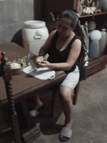 a woman sits at a table in front of a white barrel that has the letter o on it