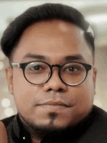 a close up of a man wearing glasses and a black shirt