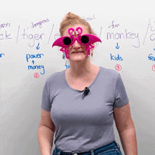 a woman wearing a pair of flamingo sunglasses stands in front of a white board that says " monkey "