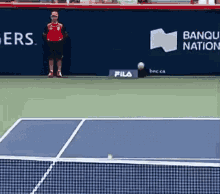 a man in a red shirt is standing on a tennis court in front of a banner for bango nation