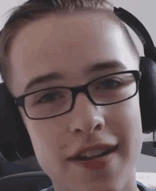 a young boy wearing glasses and headphones with a microphone on his head .