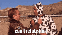 a man in a cow costume talks to a man in a sheriff 's uniform