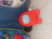 a stuffed red among us character is laying on a bed