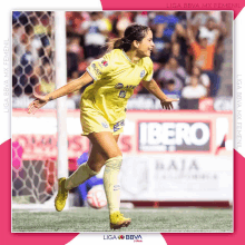 a female soccer player is celebrating a goal in front of a banner that says ibero