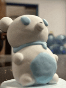 a white teddy bear with blue eyes and a blue circle on its belly