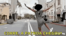 a woman in a dress is jumping in the air on a city street with her arms outstretched .