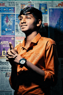 a young man wearing a watch stands in front of a wall of advertisements