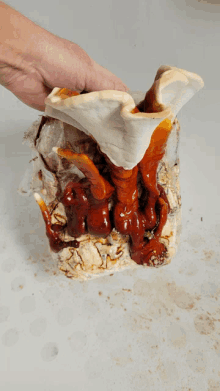 a person is holding a piece of food that is covered in liquid