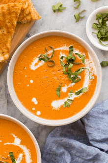 a bowl of tomato soup with a swirl of cream and basil